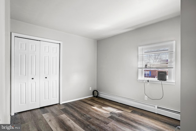 unfurnished bedroom with a closet, baseboard heating, dark wood-type flooring, cooling unit, and baseboards