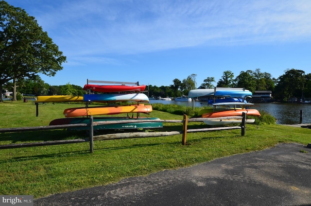 surrounding community with a water view, a dock, and a yard