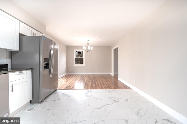 kitchen featuring marble finish floor, appliances with stainless steel finishes, an inviting chandelier, and white cabinets