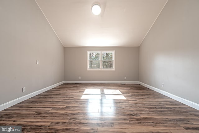 bonus room featuring dark wood finished floors, vaulted ceiling, and baseboards