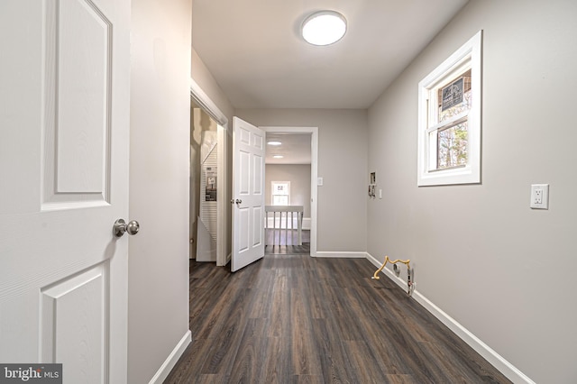 corridor featuring dark wood-style flooring and baseboards