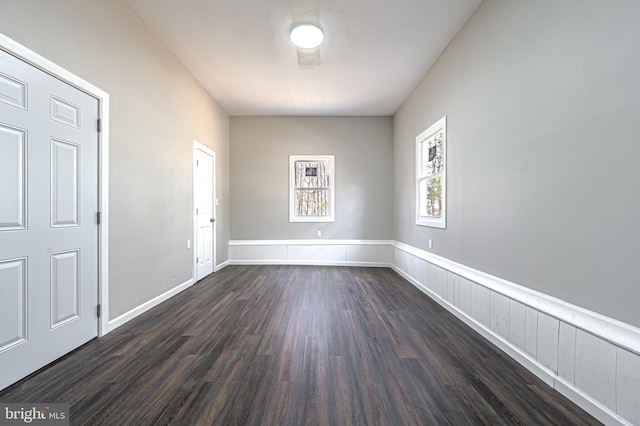 spare room featuring dark wood-style flooring and baseboards