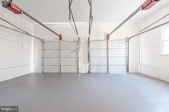 garage featuring concrete block wall and a garage door opener