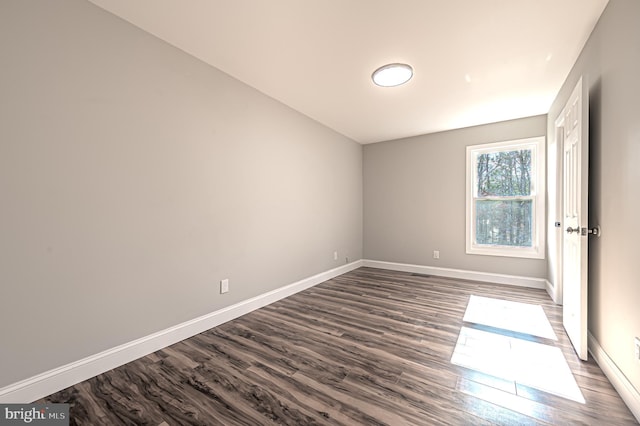 spare room with dark wood-style flooring and baseboards