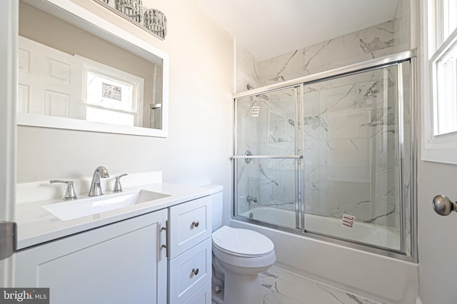 bathroom featuring toilet, vanity, a healthy amount of sunlight, marble finish floor, and combined bath / shower with glass door