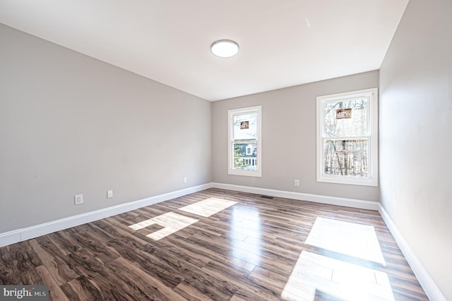 unfurnished room featuring visible vents, baseboards, and wood finished floors