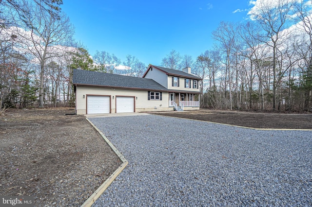 view of front of property with a chimney, roof with shingles, gravel driveway, an attached garage, and a porch