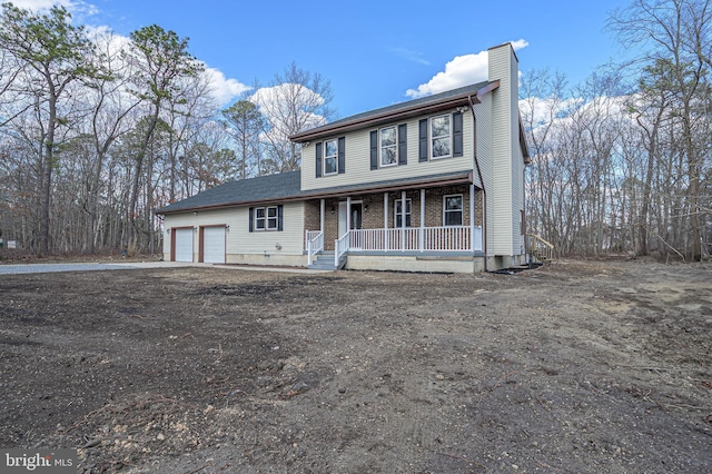 view of front of home featuring a porch, a garage, brick siding, driveway, and a chimney