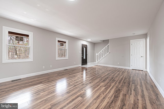 interior space with plenty of natural light, stairs, visible vents, and wood finished floors