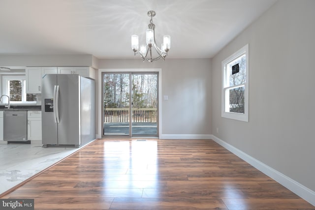 unfurnished dining area with a healthy amount of sunlight, baseboards, and a chandelier