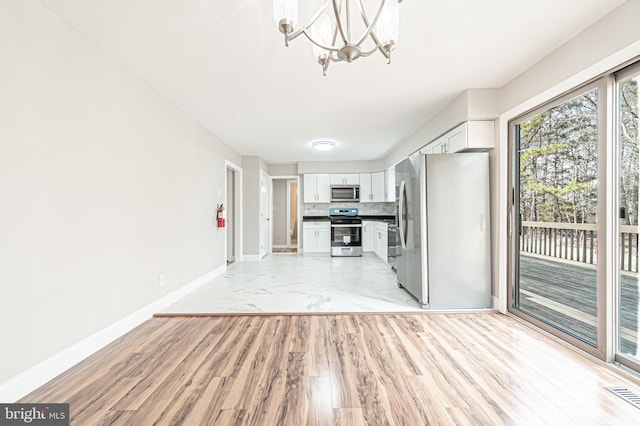 kitchen featuring stainless steel appliances, visible vents, white cabinets, baseboards, and an inviting chandelier