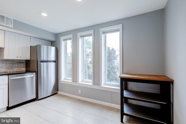 kitchen featuring visible vents, appliances with stainless steel finishes, a wealth of natural light, decorative backsplash, and dark countertops