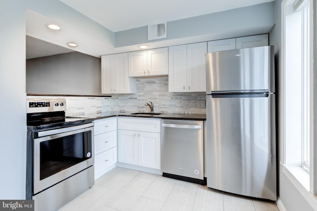 kitchen with dark countertops, visible vents, stainless steel appliances, and a sink