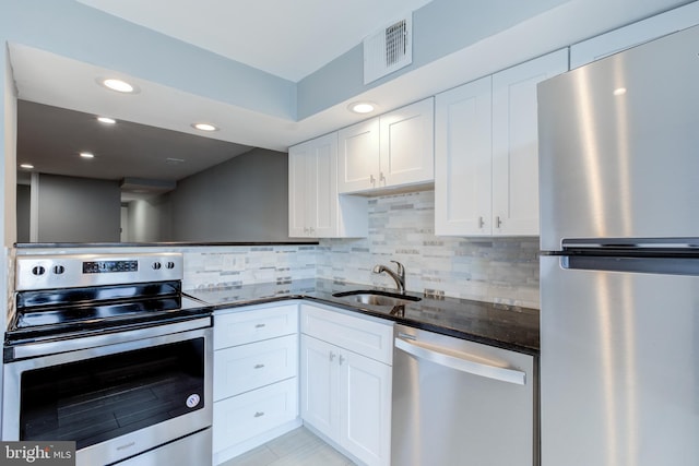 kitchen featuring visible vents, dark stone counters, appliances with stainless steel finishes, white cabinetry, and a sink