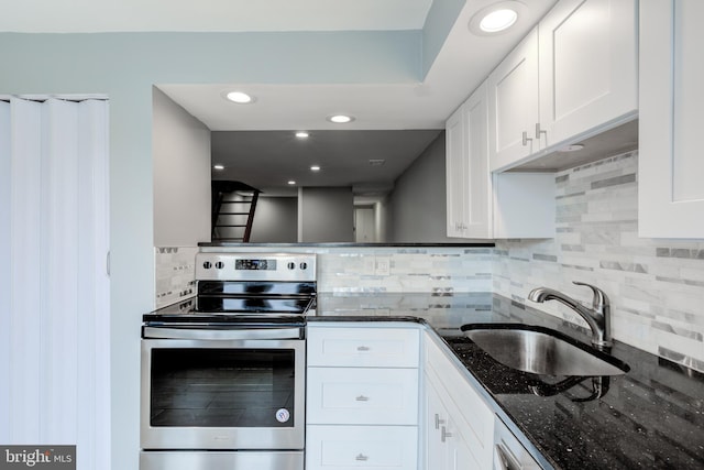 kitchen with dark stone countertops, white cabinetry, a sink, and stainless steel electric range