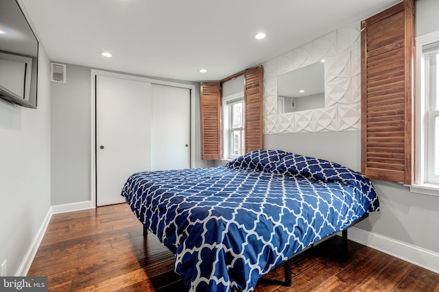 bedroom with a closet, visible vents, baseboards, and hardwood / wood-style floors