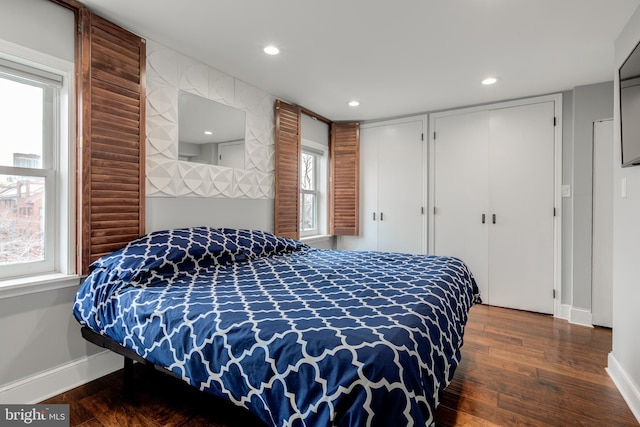 bedroom featuring multiple windows, wood finished floors, and two closets