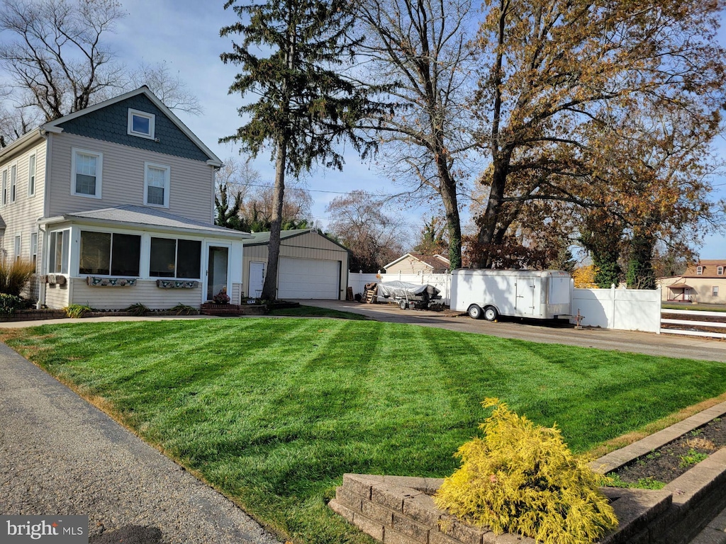 view of front facade with an outdoor structure, a detached garage, a front lawn, and fence