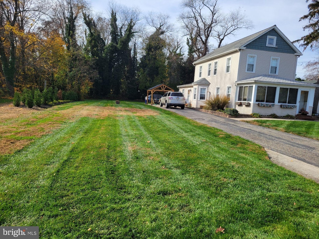 view of yard featuring aphalt driveway and a sunroom