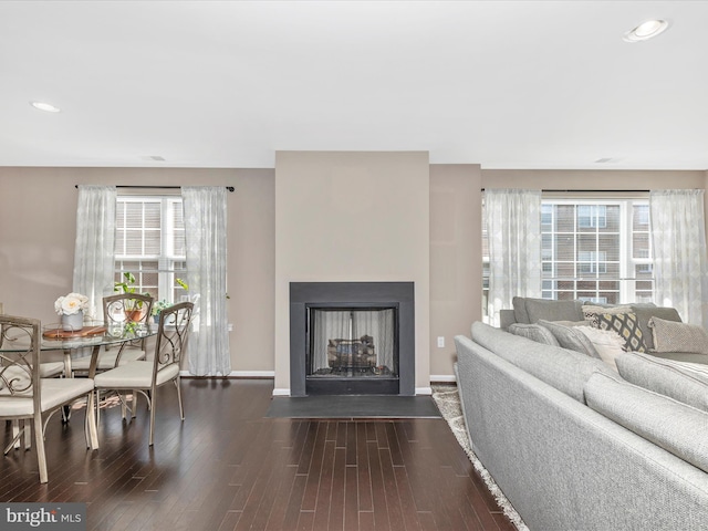 living area with dark wood finished floors, a fireplace with flush hearth, and baseboards