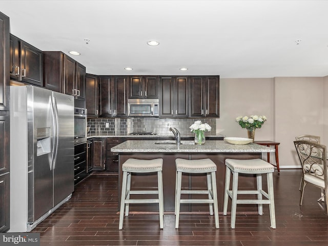 kitchen with a kitchen breakfast bar, tasteful backsplash, appliances with stainless steel finishes, and wood tiled floor