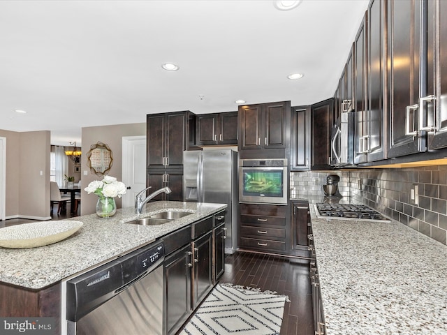 kitchen with tasteful backsplash, dark wood finished floors, an island with sink, appliances with stainless steel finishes, and a sink