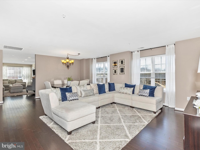 living area with an inviting chandelier, dark wood-style floors, visible vents, and baseboards