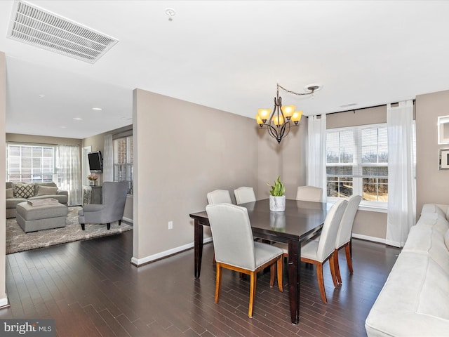 dining area featuring dark wood-type flooring, a notable chandelier, baseboards, and visible vents