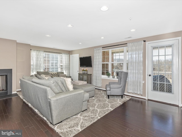 living area with wood finished floors, plenty of natural light, a fireplace, and visible vents