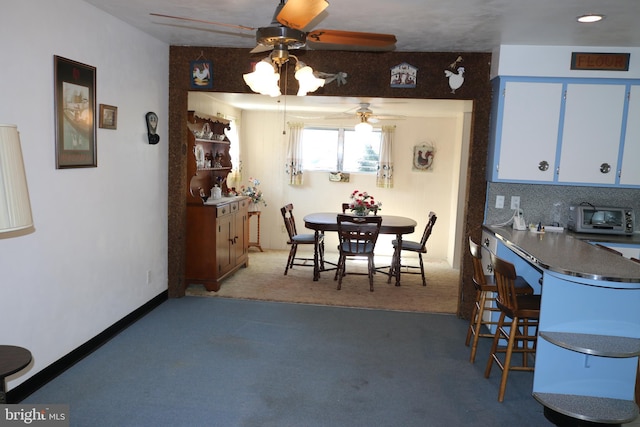 dining room featuring a toaster, light colored carpet, and baseboards