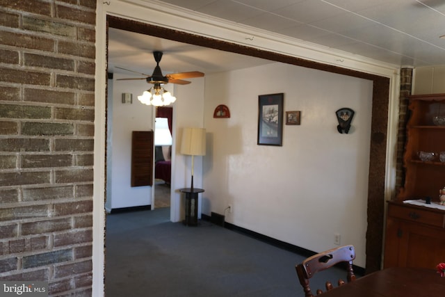 interior space with brick wall, baseboards, and ceiling fan