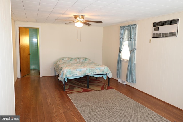 bedroom featuring a wall mounted air conditioner, visible vents, wood finished floors, and a ceiling fan