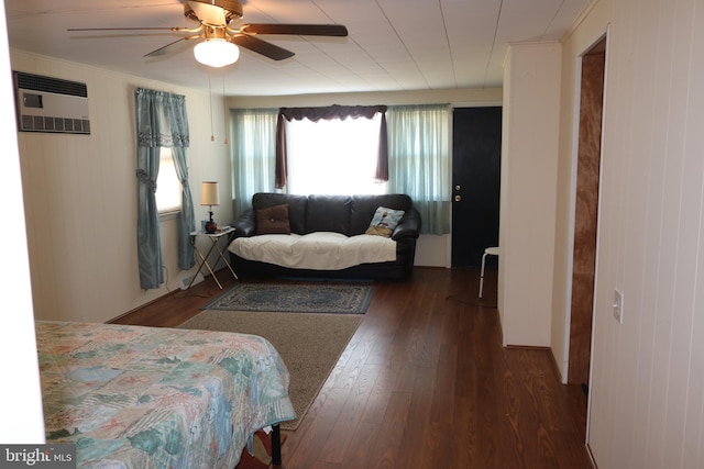 bedroom with a wall unit AC, wood finished floors, and ceiling fan