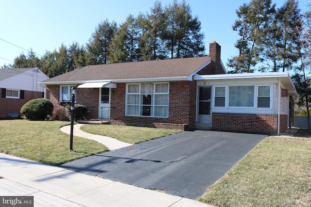 ranch-style home with brick siding, a chimney, a front lawn, and a shingled roof