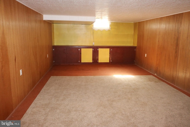 finished basement with carpet, wood walls, and a textured ceiling