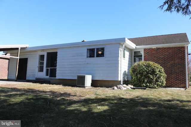 view of property exterior featuring cooling unit, brick siding, and a yard