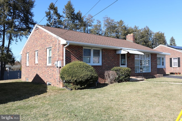 single story home featuring a front lawn, brick siding, roof with shingles, and a chimney