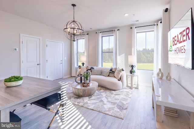 living room with an inviting chandelier, baseboards, visible vents, and wood finished floors