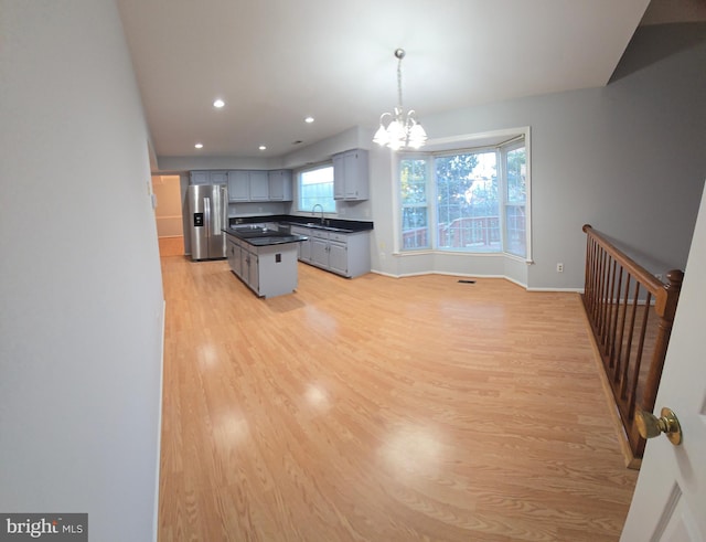 kitchen featuring light wood-type flooring, dark countertops, a notable chandelier, and stainless steel fridge with ice dispenser