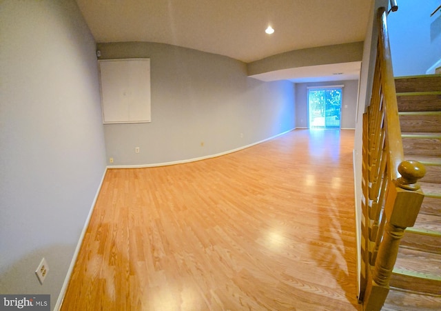 empty room featuring light wood-type flooring, baseboards, and stairway