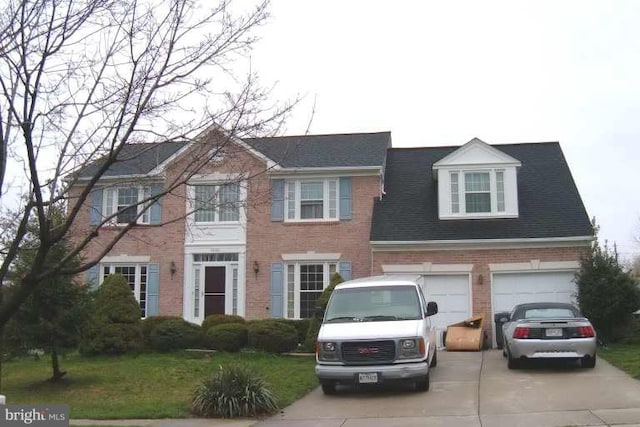 colonial inspired home featuring concrete driveway and brick siding