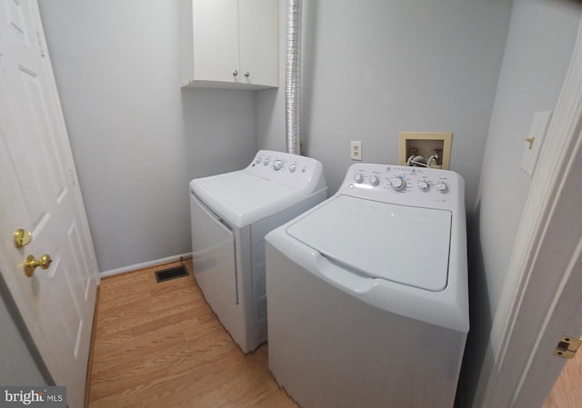 washroom featuring visible vents, baseboards, light wood-style floors, cabinet space, and washing machine and clothes dryer