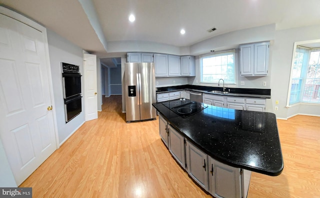 kitchen featuring black appliances, light wood finished floors, a sink, and visible vents