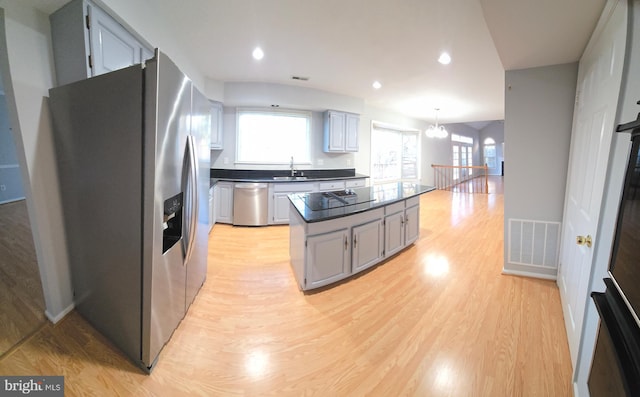 kitchen featuring stainless steel appliances, light wood-type flooring, dark countertops, and visible vents