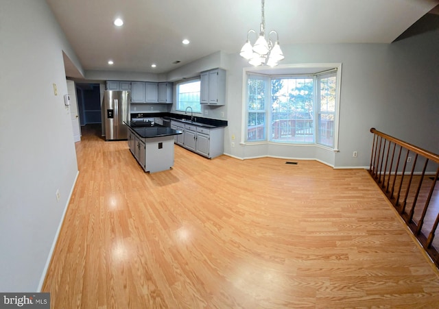 kitchen with gray cabinetry, baseboards, light wood-type flooring, stainless steel refrigerator with ice dispenser, and dark countertops