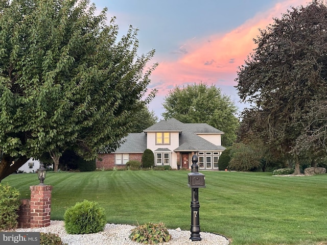 traditional home featuring a lawn and brick siding