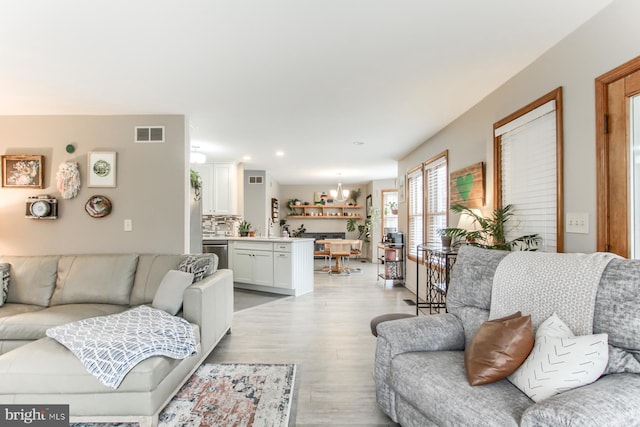 living area with recessed lighting, light wood-style floors, visible vents, and a chandelier