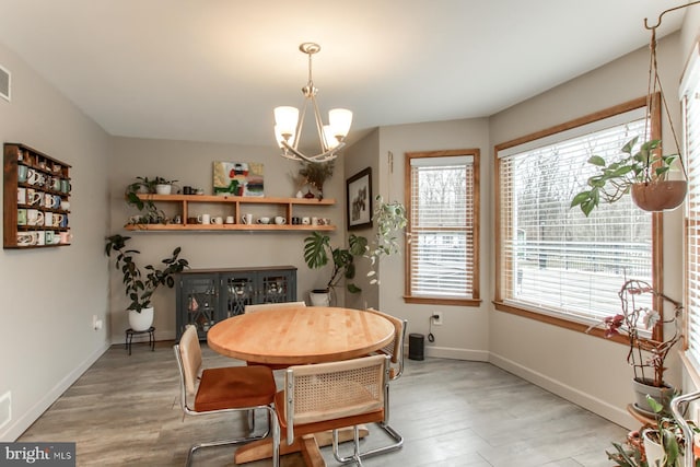 dining room featuring baseboards, an inviting chandelier, and light wood finished floors