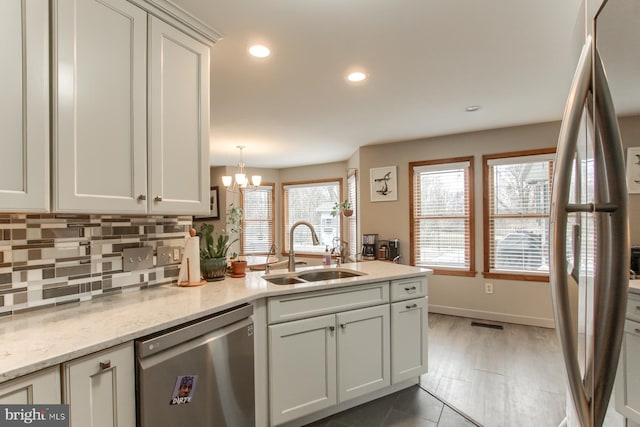 kitchen with a peninsula, recessed lighting, a sink, appliances with stainless steel finishes, and backsplash