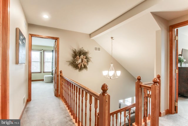 hall with visible vents, an upstairs landing, a notable chandelier, lofted ceiling with beams, and light colored carpet